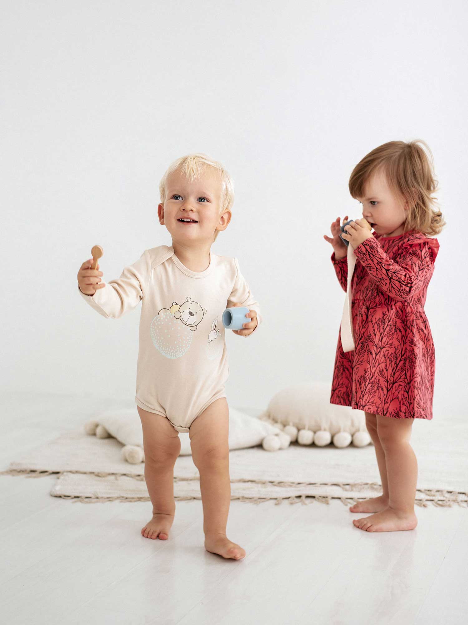 Cute blonde kid wearing infant bodysuit Bear and Bunny 368, sitting next to a girl that weares the baby dress Squirrel 361