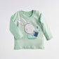 The pajama blouse from the newborn pajamas set Bear and Bunny 381 features a cute bunny reading in a book, while a small bird takes a look inside.