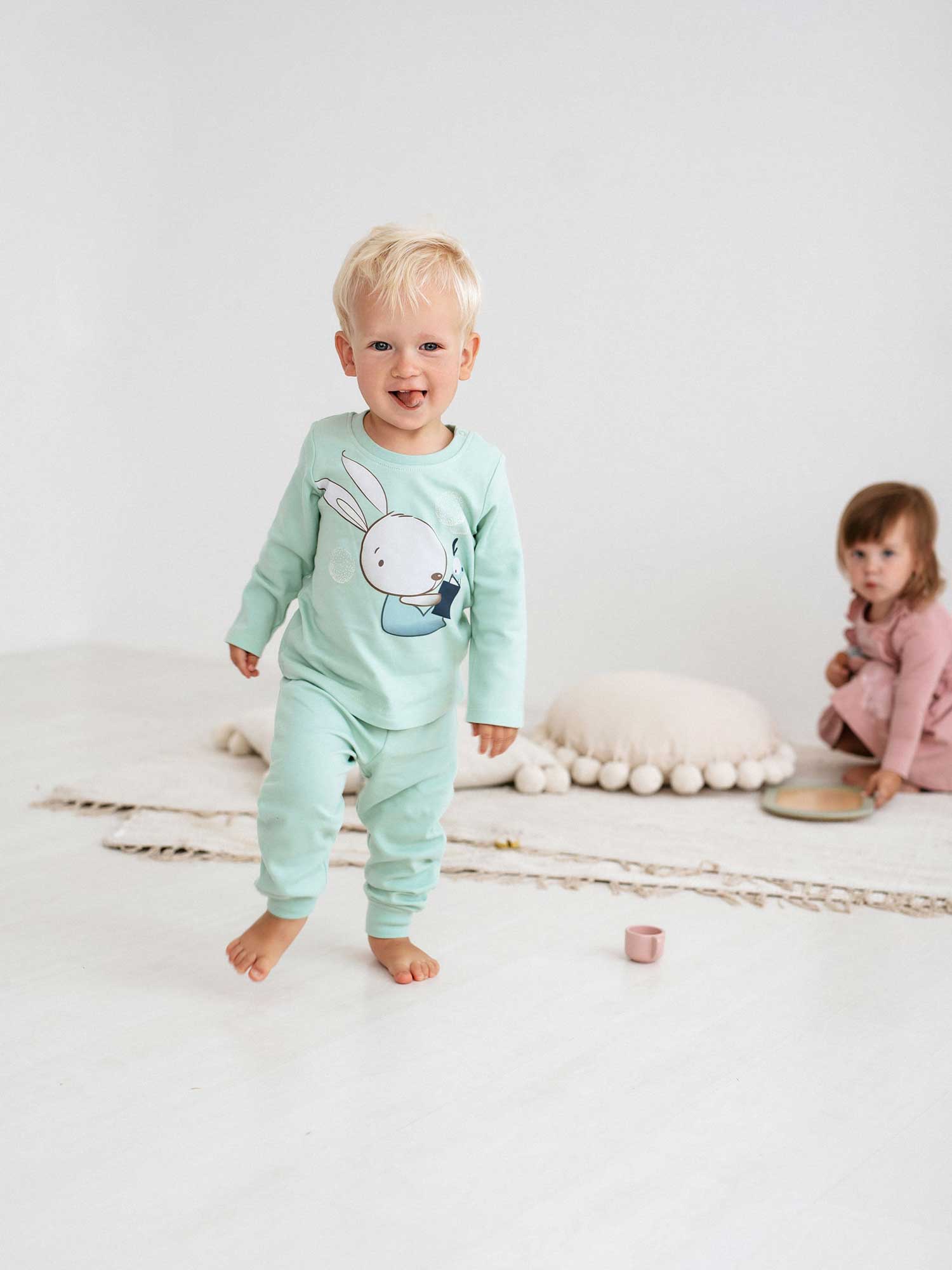 A cute blonde kid wearing Bear and Bunny 381 newborn pajamas.